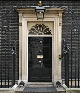 10 Downing Street door by Jdforrester crop from original by Prime Minister's Office, HM Government. (2010 Official Downing Street pic.jpg) [OGL (http://www.nationalarchives.gov.uk/doc/open-government-licence/version/1/)], via Wikimedia Commons